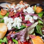 Nancy's House Salad - Fresh spinach + spring mix + iceberg + cherry tomatoes + candied walnuts + cranberries + crumbled bacon + red onion + blue cheese crumble + croutons + your choice of dressing