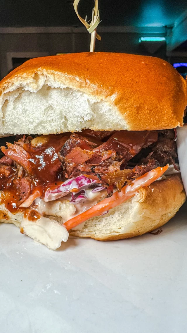 Bite into the indulgence of our St. Louis Rib Sandwich, where our famous house-smoked ribs, now deboned, overflow from a toasted brioche roll. Generously topped with our rich bourbon barrel BBQ sauce and mounds of crisp coleslaw, each sandwich is a towering testament to BBQ perfection. Served with our house-made chips, it’s a feast that’s as big on flavor as it is on size. Ready for the challenge? Come and get it!